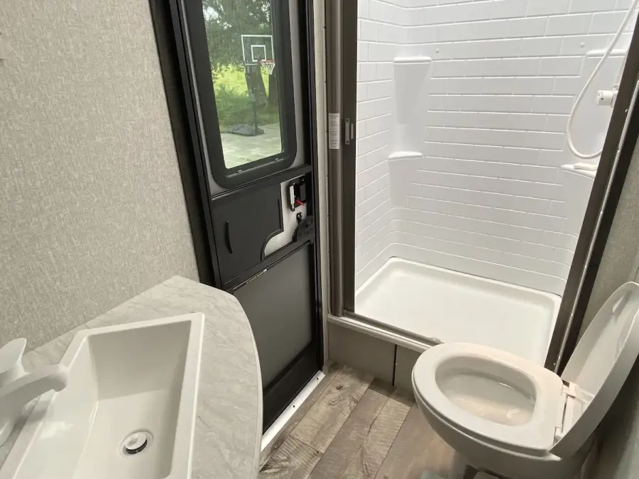 The camper bathroom has a single lav, toilet, and a stand-up shower.